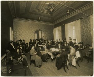 Photo Credit: The Rooms Provincial Archives: A 51-112; A work committee in the Ball Room of Government House. Note that some of the women are sewing by hand and machine; others are knitting.
